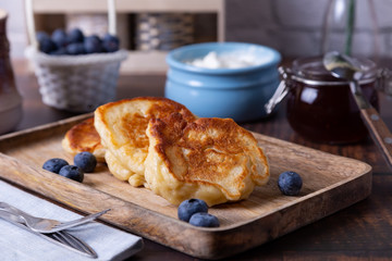 Fritters with sour cream, jam and blueberries. The traditional Russian dish. Close-up.
