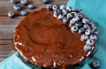 berry pie ,1 round chocolate homemade cake with fresh blueberries on a blue towel and wooden brown background