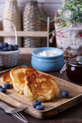 Fritters with sour cream, jam and blueberries. The traditional Russian dish. Close-up.