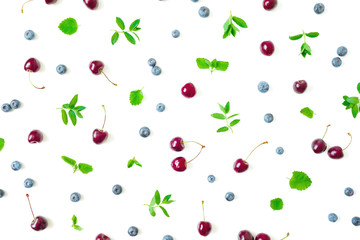 Blueberries and cherry with mint leaves on white background. Top view