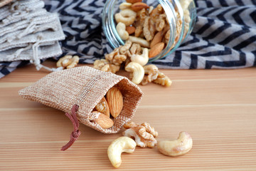 Nuts in a bag and a glass jar on a wooden background. Suitable for advertising background