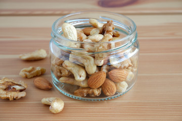 Nuts in a glass jar on a wooden background. Suitable for advertising background
