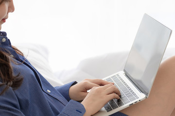 Close up young woman use laptop and sitting on white bed in morning.