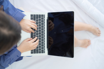 Close up top view young woman use laptop and sitting on white bed in morning.