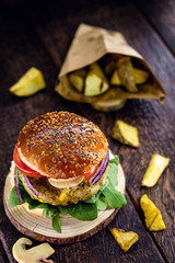 Vegetarian hamburger, sandwich made without meat, with portion of french fries. Sandwich with mushroom, tomato, lettuce, arugula, protein and mushroom.
