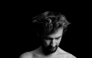 portrait of a guy with a beard and tousled hair on a black background