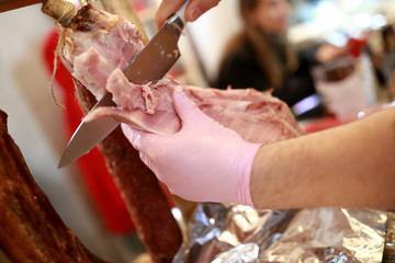 Obraz na płótnie Canvas Seller cuts slice of pork ham