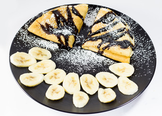 Chocolate crepes with banana on the plate, studio shot
