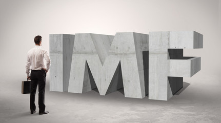 Obraz premium Rear view of a businessman standing in front of IMF abbreviation, modern technology concept