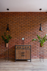 Wooden dresser in room with brick wall