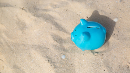 Fototapeta na wymiar The concept of accumulating money for a summer vacation Blue piggy bank pig on warm fine sea sand savings on vacation
