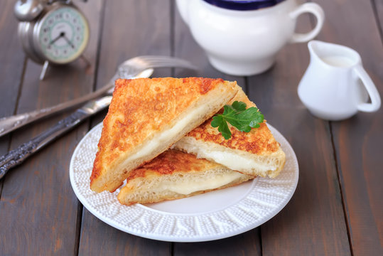 Italian grilled cheese sandwich Mozzarella in carrozza. Sliced fried sandwich with melted mozzarella on a plate. Dark wooden background, Selective focus.