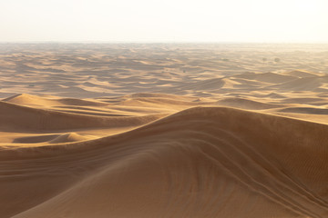Fototapeta na wymiar Photo of the desert at sunset Dubai 2020. Sand dunes of the desert with traces of car wheels