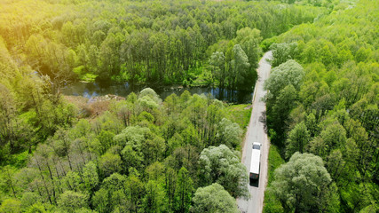 Commercial truck driving along the rural road between forest