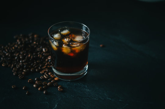 Cold Brew Coffee in Whiskey glass on a countertop with coffee beans