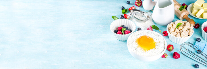 Berry cake baking recipe. Summer cooking baking background with assorted berries, baking ingredients, tools and utensils, light blue sun lighted wooden background flat lay top view copy space