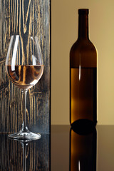 Bottle and glass of white wine on a black table.