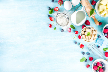 Berry cake baking recipe. Summer cooking baking background with assorted berries, baking ingredients, tools and utensils, light blue sun lighted wooden background flat lay top view copy space