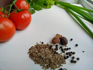 dried spices: dill, black pepper, nutmeg on the background of tomatoes, onion, fresh salad, celery