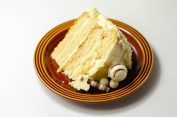 A piece of layered white cream cake with confectionery decorations