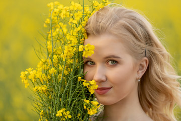 Close-up portrait of Beautiful blond young teen girl smell a bouquet of yellow flowers. Pleasure, nature, travel, vacation.