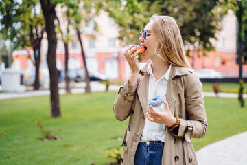 Junk food. Happy delighted woman in casual clothes eating donut with expression of big pleasure, temptation to bite doughnut, appetizing bakery. Sweet tooth,indulgence, gluttony, unhealthy lifestyle
