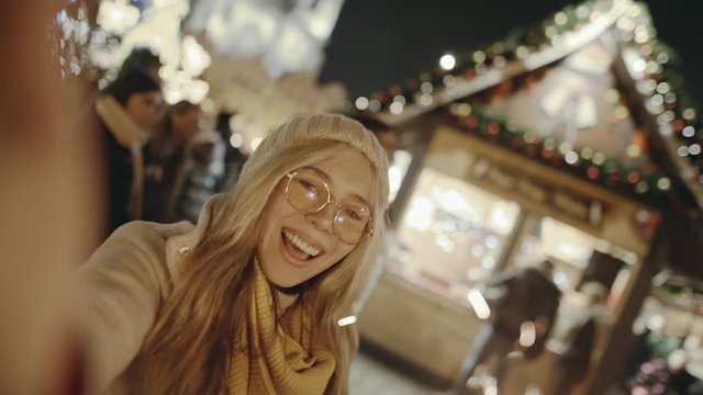 Selfie time, girl blogger is making video and photo for her social page at the street fair on the central Square of Prague. Gorgeous blonde smiling and burning bright sparklers on New Year's Eve.