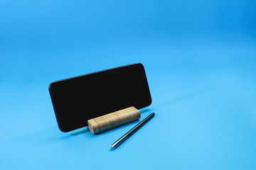 Smartphone and stylus pen on blue background 