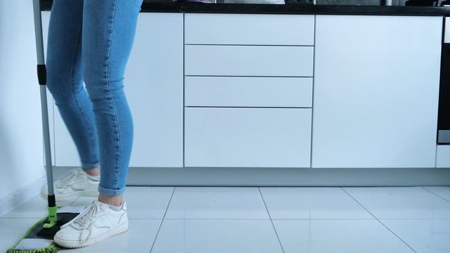 Woman washing white kitchen floor with special swob, cleaning service, close-up