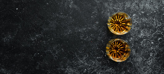 Whiskey in glasses on black stone table. Top view. Free space for your text.