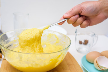 the dough for cupcakes made of rice flour, butter, eggs, sugar runs off the spoon. close-up of the dough texture in a transparent dish
