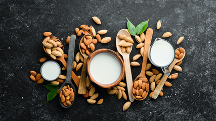 Almond milk and almonds on black stone background. Top view. Free space for your text.