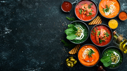 Fototapeta na wymiar Set of colored soups. Spinach soup, tomato cream soup and carrot puree soup. Healthy food. On a black stone background.