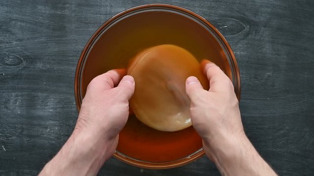 Kombucha SCOBY disk Symbiotic culture of bacteria and yeast in the hand of an unrecognizable man. Cooking healthy probiotic kombucha drink. Dark rustic wooden table. Top view