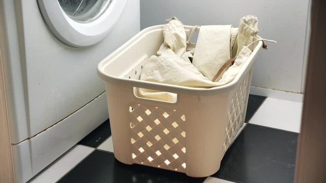 Throwing dirty laundry inside laundry basket near washing machine