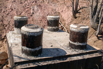 Construction of an underground concrete building with four manholes. Cast-iron covers covering sewer mines.  Сoncept of underground utilities: heat, gas, cable networks, water supply and sewage.