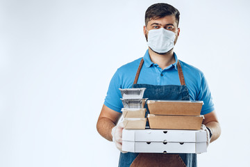Fototapeta na wymiar Delivery man in protective mask and medical gloves holding takeaway food. Compliance with the hygiene rules while covid-19 pandemic