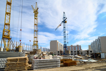 Photos of high-rise construction cranes and an unfinished house against a blue sky. Photographed on...