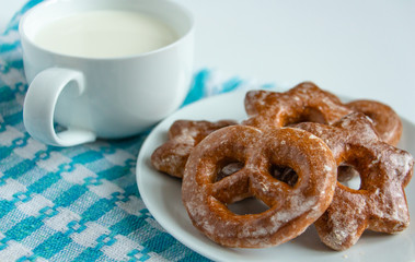 fragrant gingerbread cookies on a white plate with a cup of warm fresh milk, white background, blue napkin, delicious dessert, creating a feeling of homeliness