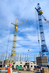 Photos of high-rise construction cranes and an unfinished house against a blue sky. Photographed on a wide angle lens