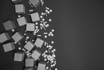 
pills and wooden cubes scattered, black and white image