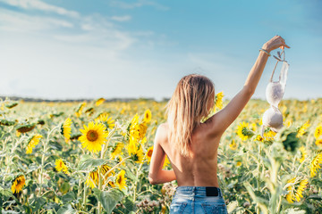 Topless girl swings bra in sunflowers
