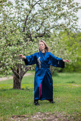 a girl martial artist practices tai Chi in a wild apple garden