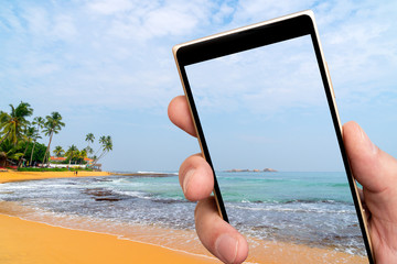 Tropical beach on smartphone screen. Coastal reef. Soft focus background.