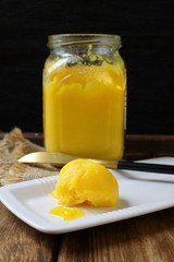 Ghee on a white plate, close-up. A healthy high fat dairy product. Clarified butter and glass jar on a wooden vintage table, macro.