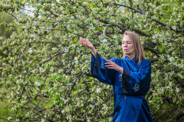 woman martial master practicing tai Chi in the blooming garden