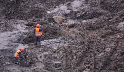 Workers in the mud of a construction site at the stage of excavation; construction of a supermarket...