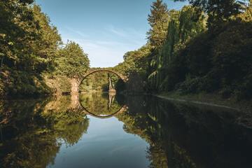 Fototapeta premium Fantastic morning scene of Azalea and Rhododendron Park Kromlau, Germany, Europe. Splendid summer view of Rakotz Bridge Rakotzbrucke, Devil's Bridge .