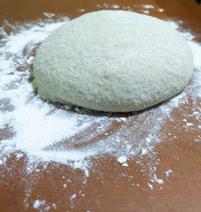 Raw rolled from a dough for wholemeal bread on a wooden table
