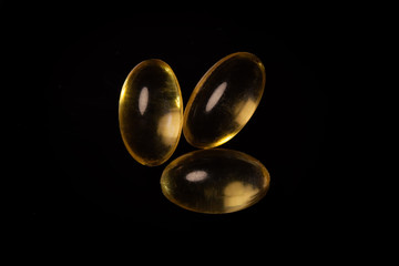 Vitamin D3, golden, yellow vitamin capsules, high quality on a black background